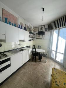 a kitchen with white cabinets and a table and chairs at ALLOGGIO VISTA MARE LOANO in Loano