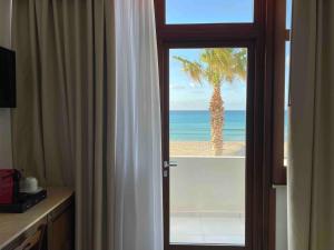 een deur naar een kamer met een palmboom op het strand bij Hotel Egitarso Sul Mare in San Vito lo Capo