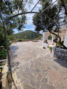 a stone courtyard with an archway with a mountain in the background at Villa Quattro Archi in Geremeas