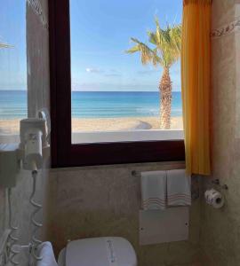 a bathroom with a window with a view of the beach at Hotel Egitarso Sul Mare in San Vito lo Capo