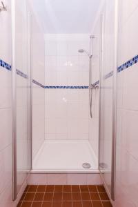 een douche in een badkamer met witte tegels bij Landhaus Greetsiel am Hafen "Ankerplatz" in Krummhörn
