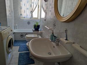 un bagno con lavandino, WC e specchio di Alghero, ottimo appartamento a 100 m. dal mare ad Alghero Altre 13 foto