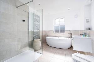 a white bathroom with a tub and a toilet at Beautiful Big Family Home - Sleeps 10, Park 3 Cars in Meanwood