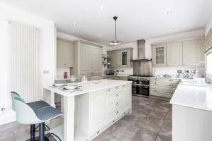 a kitchen with white cabinets and a blue chair at Beautiful Big Family Home - Sleeps 10, Park 3 Cars in Meanwood