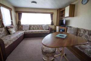a living room with a couch and a table at 8 Berth Spacious Caravan By The Beach In Norfolk Ref 50059g in Great Yarmouth