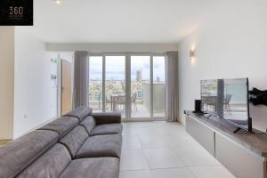 salon z kanapą i telewizorem z płaskim ekranem w obiekcie Stunning 3BR penthouse, opposite the harbour by 360 Estates w mieście Tal-Pietà