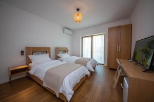 a bedroom with two beds and a flat screen tv at Bujtina GleAlb in Tepelenë