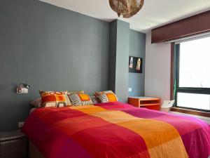 Apartamento zona Ria do Burgo في لا كورونيا: غرفة نوم مع سرير كبير مع بطانية ملونة