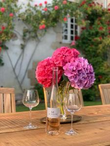 einen Tisch mit zwei Weingläsern und einer Vase Blumen in der Unterkunft Manoir de La Ville Durand in Binic