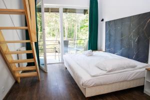 a bedroom with a bed and a ladder and a balcony at Forrest Jantar in Jantar