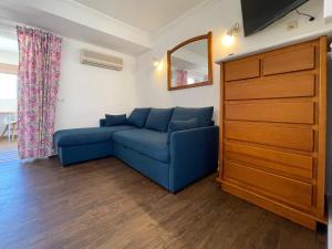ein Wohnzimmer mit einem blauen Sofa und einer Kommode in der Unterkunft Sofeelings, Estudio Sol, Baixa de Albufeira in Albufeira