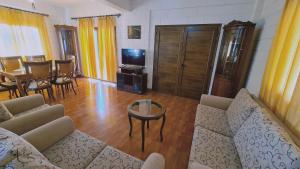 ein Wohnzimmer mit einem Sofa, einem TV und einem Tisch in der Unterkunft STAY Pernera House in Ayia Napa