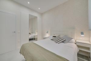 a white bedroom with a bed and two night stands at Apartamentos Pamplona Confort by Clabao in Pamplona