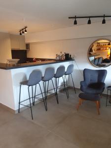 a kitchen with a bar with four chairs and a mirror at POROS Summer Apartment - Neorio in Poros