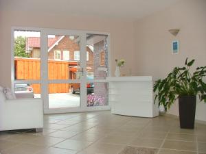 a living room with a sliding glass door with a plant at Hotel Thule in Carolinensiel