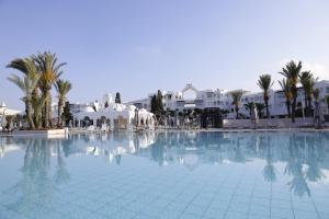 une grande piscine avec des palmiers et des bâtiments dans l'établissement The Mirage Resort & SPA, à Hammamet
