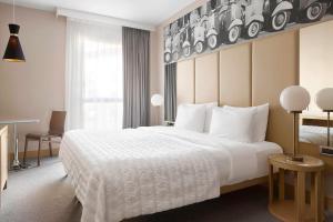 una camera d'albergo con un grande letto bianco e una finestra di Le Meridien Visconti Rome a Roma