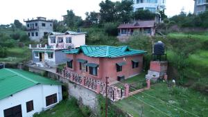 an old house with a green roof on a hill at Sky touch cottage & stays in Mukteswar