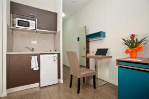 a small kitchen with a desk and a table with a laptop at Appart Hotel Odalys City Tours Le Jardin des Lettres in Tours