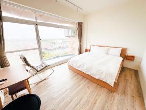 een slaapkamer met een bed en een groot raam bij 艾睏khùn行旅 in Donggang