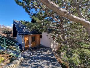 a small house with a wooden door next to a tree at Chalet Saint-Michel-de-Chaillol, 5 pièces, 9 personnes - FR-1-393-168 in Saint-Michel-de-Chaillol