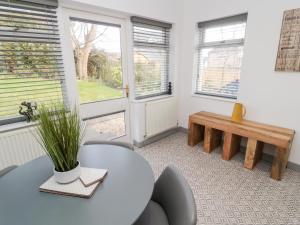 a room with a table and a bench and windows at The Annexe in Berwick-Upon-Tweed