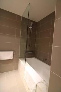 a bathroom with a shower and a bathtub with a glass door at Heavenly Chic Apartment & only 30m to Bridge Road 01578 in Melbourne