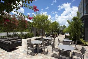 un patio con mesas, sillas y árboles en Courtyard by Marriott Orlando South/Grande Lakes Area, en Orlando