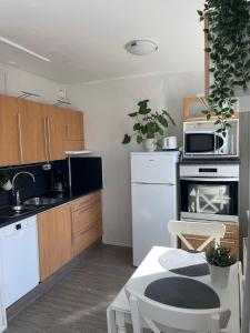 a kitchen with white appliances and wooden cabinets at City Apartment Maaherrankatu in Kuopio