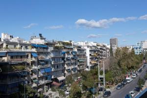 una calle de la ciudad con edificios de apartamentos altos y coches en La Residence Athens, en Atenas