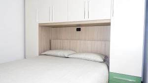 Affittimoderni Bergamo Curno CUMA11 في Curno: سرير في غرفة بها دواليب بيضاء