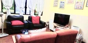a living room with two chairs and a television at Villa Ceferina Bohol in Tagbilaran City