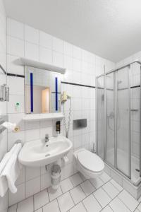 a bathroom with a sink and a shower and a toilet at HOTEL BREMER TOR, Bestes Hotelfrühstück, Self-Check-In 24 h in Vechta