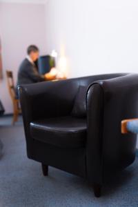 Ein Mann, der auf einem schwarzen Stuhl in einem Zimmer sitzt. in der Unterkunft HOTEL BREMER TOR, Bestes Hotelfrühstück, Self-Check-In 24 h in Vechta