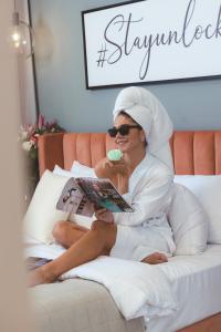 a woman sitting on a bed reading a book at Unlock J One Downtown Dubai in Dubai