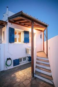 a white house with blue shutters and a staircase at "Triacanthos" 2 bedroom house in Moutsoúna