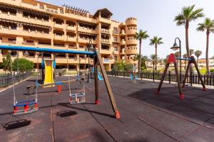 a playground in front of a building with palm trees at Dream Sea Apartments in Almerimar