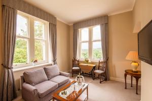 a living room with a couch and two windows at Ashdown Park Hotel in Forest Row