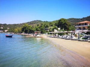 a beach with chairs and a boat in the water at POROS Summer Apartment - Neorio in Poros