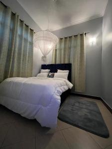 a bedroom with a large white bed and a chandelier at Romantic, Stunning & Authentic Ensuited Master Bedroom in Dar es Salaam