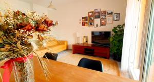 una sala de estar con una mesa con un jarrón de flores en Vive la vida: Torremolinos (1ª línea), en Torremolinos