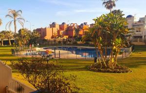 a pool in a park with palm trees and buildings at Vive la vida: Torremolinos (1ª línea) in Torremolinos