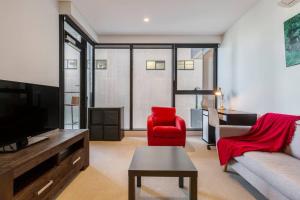 a living room with a couch and a red chair at Nice 1 bedroom close to Albert Park Lake 02053 in Melbourne