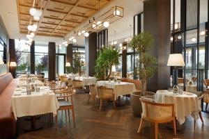 a restaurant with white tables and chairs and windows at Four Points by Sheraton Prishtina City in Prishtin&euml;