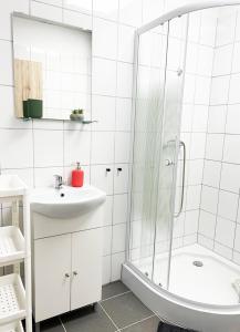a white bathroom with a shower and a sink at Árkádia Vendégház in Lábatlan