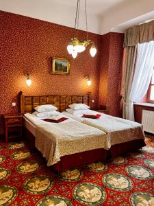 2 Betten in einem Zimmer mit roten Wänden in der Unterkunft Hotel Zamek Ryn in Ryn
