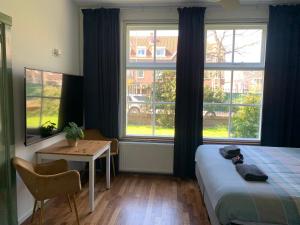 a bedroom with a bed and a table and windows at B&B Bommelsteijn in Dordrecht