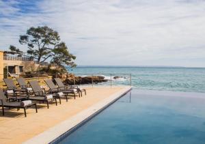 una piscina con sedie accanto all'oceano di Hotel Hospes Maricel y Spa a Cas Català