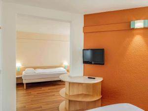 Pokój z łóżkiem i telewizorem na ścianie w obiekcie ibis Bochum Zentrum w mieście Bochum