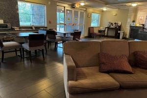 a living room with a couch and a table and chairs at Baymont by Wyndham College Station in College Station